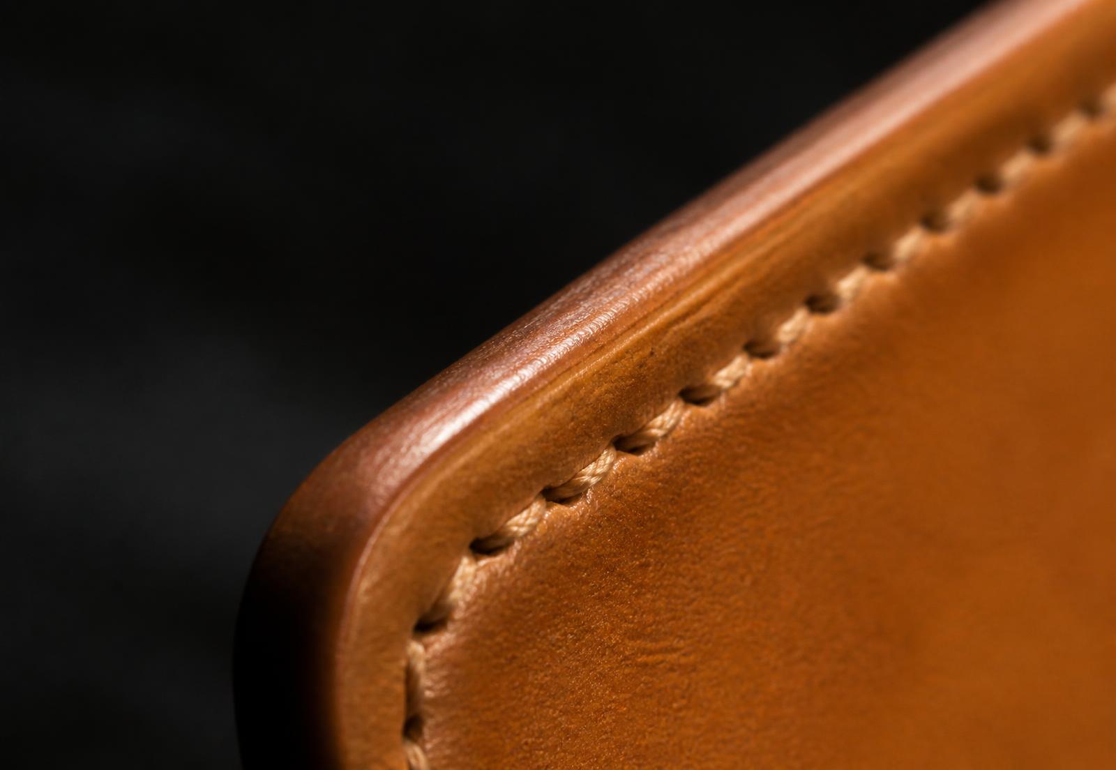 Macro detail of hand-burnished tan leather edge and stitching